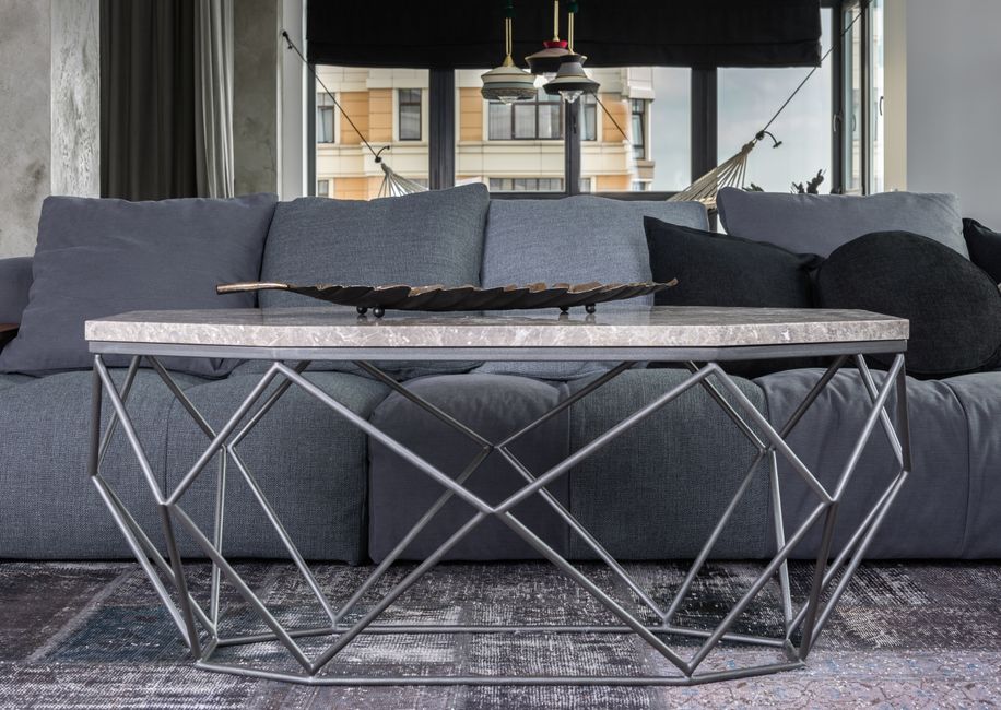 Interior of cozy living room with comfortable gray couch and marble unusual table
