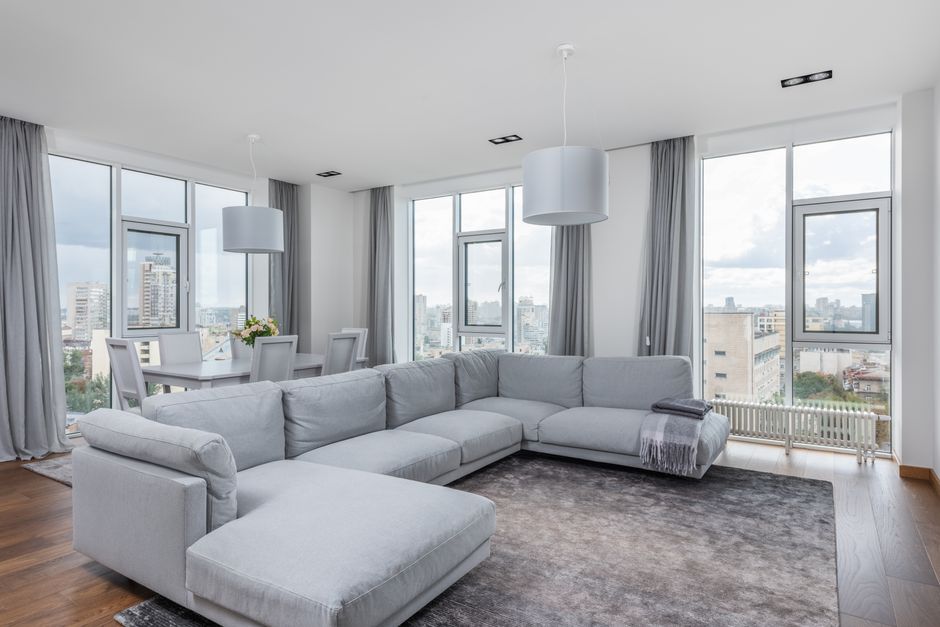 Interior of contemporary spacious living room with large comfortable sofa and panoramic windows in daytime